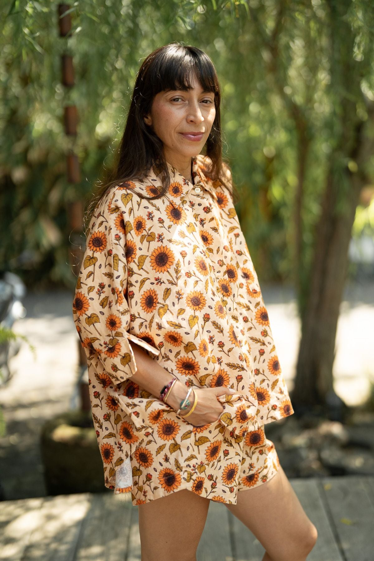 Three quarter view of the Sun Offering Suka Set, sunflower print linen top and shorts in a Bali garden