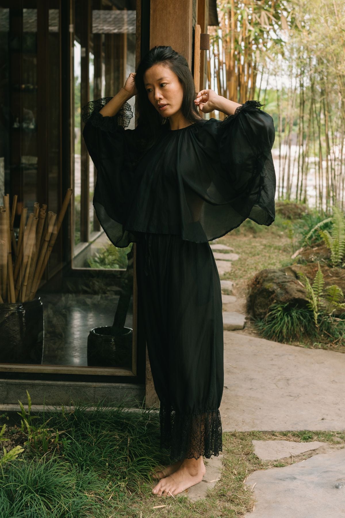 The Anusara Evening Set in Dark Moon Black silk and cotton, arms raised to show the full sleeves, hand stitched in Bali by Myrah Penaloza.