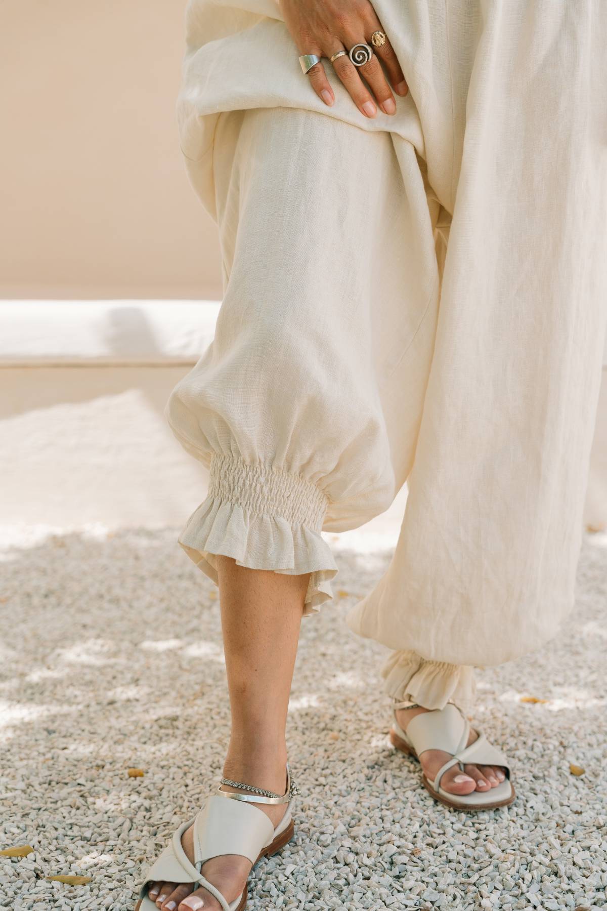 Detail of the ruffled, elastic-gathered ankle cuff on the Monaya Playsuit by Myrah Penaloza, in Moonlight stone washed linen. Handcrafted in Bali, worn with leather sandals.