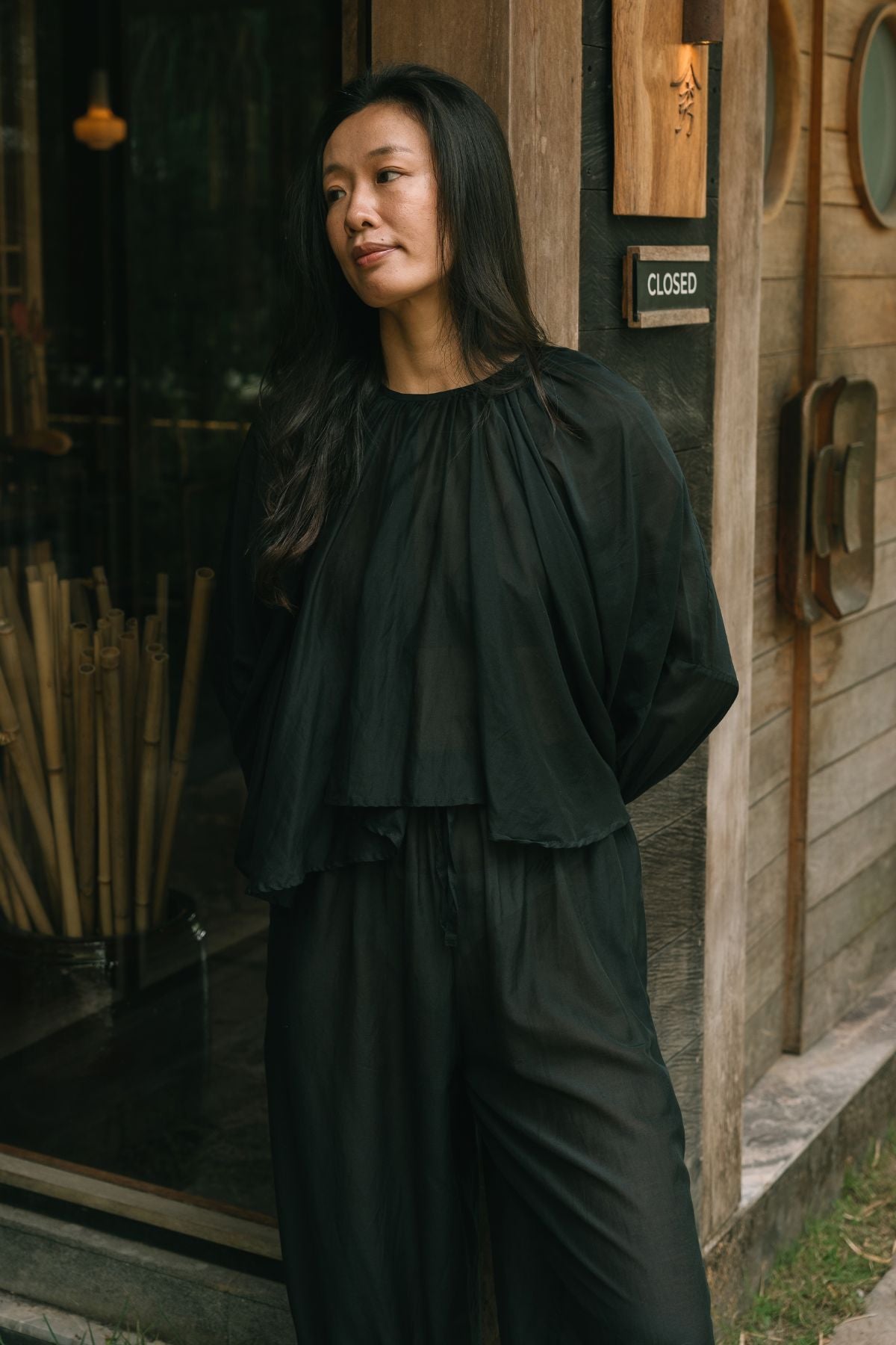 Relaxed portrait in the Anusara Evening Set by Myrah Penaloza, the gathered neckline of the silk and cotton top in Dark Moon Black.