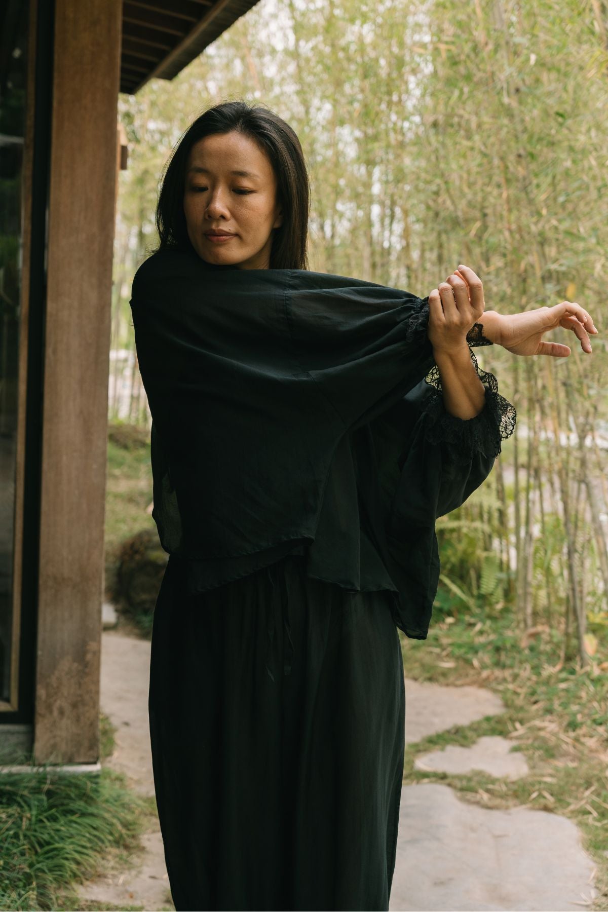 Stretching in the Anusara Evening Set, showing the soft drape of the Dark Moon Black silk and cotton top.